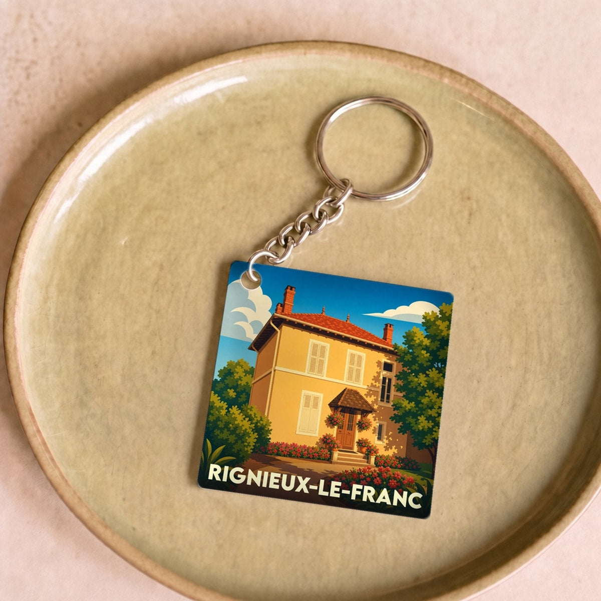 Porte-clés souvenir de la ville de Rignieux-le-Franc avec une illustration stylisée.