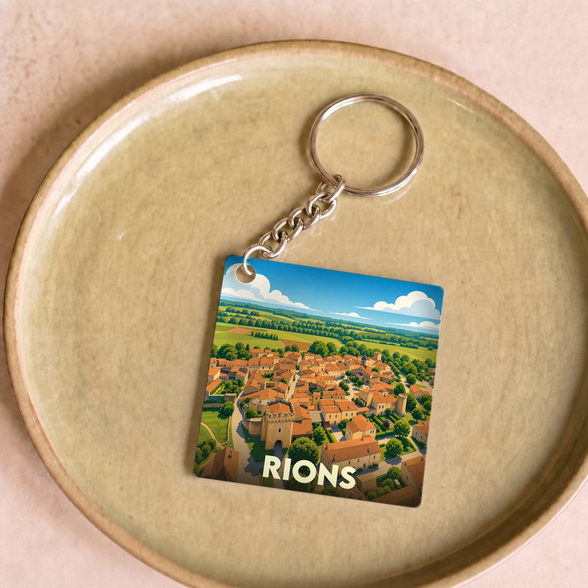 Porte-clés souvenir de la ville de Rions avec une illustration stylisée.