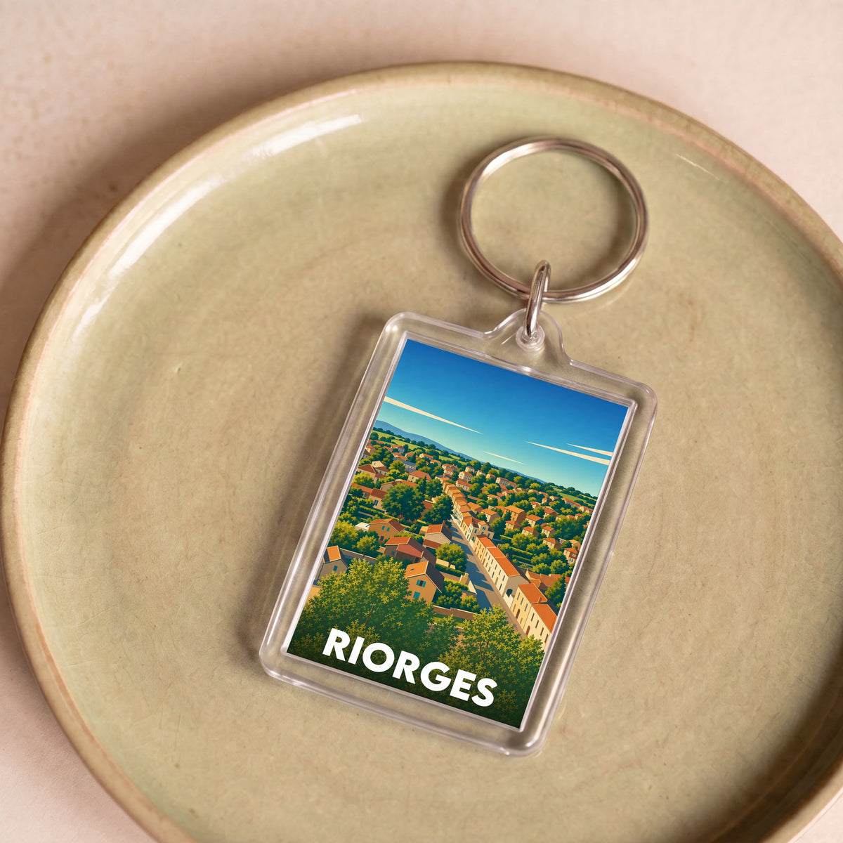 Porte-clés souvenir de la ville de Riorges arborant une illustration paysagère stylisée.
