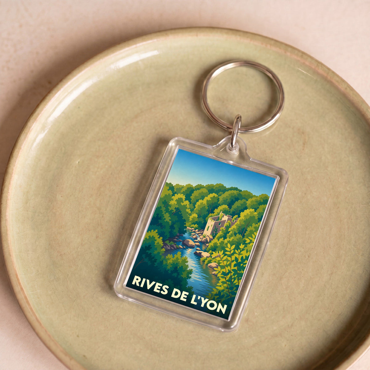 Porte-clés souvenir de la ville de Rives de l'Yon avec une illustration stylisée d'un paysage de rivière et de forêt.
