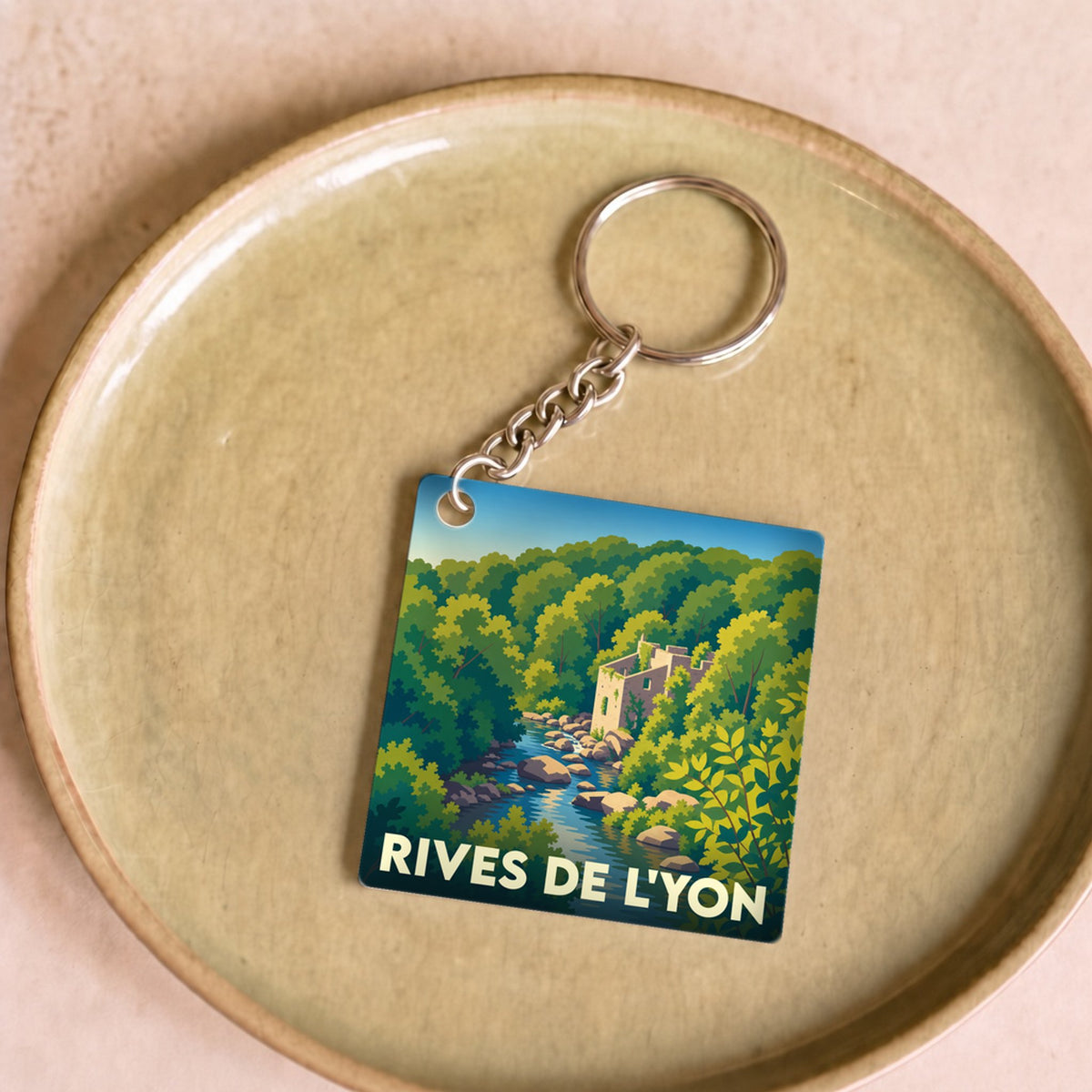 Porte-clés souvenir de la ville de Rives de l'Yon avec une illustration stylisée d'un paysage de rivière et de forêt.