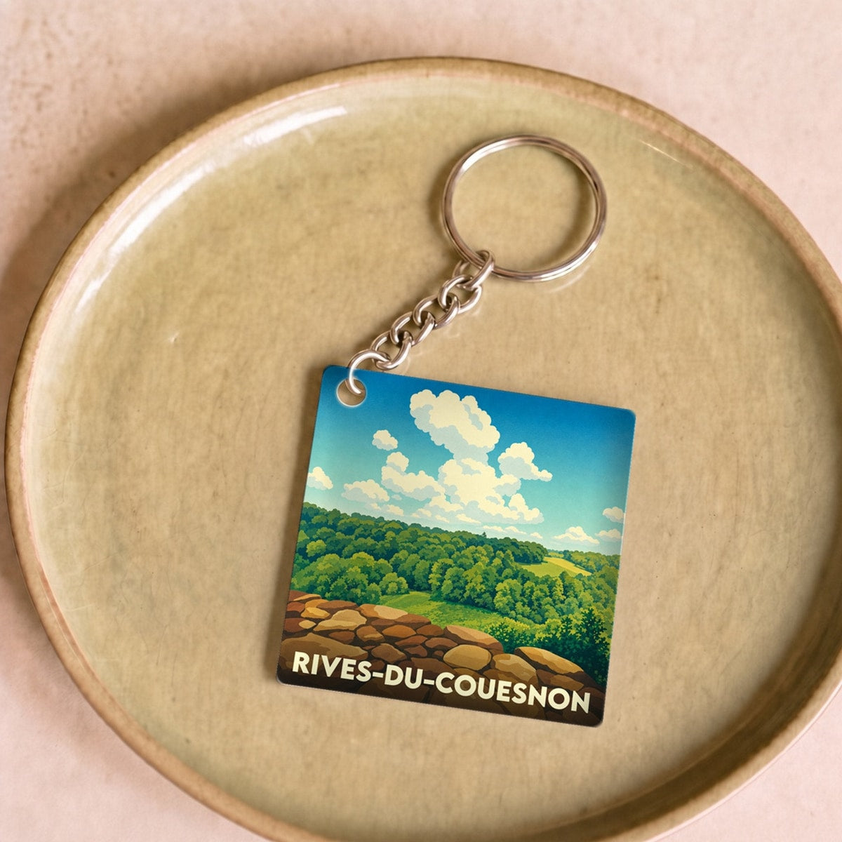 Porte-clés souvenir de la ville de Rives-du-Couesnon avec une illustration stylisée de paysage naturel.