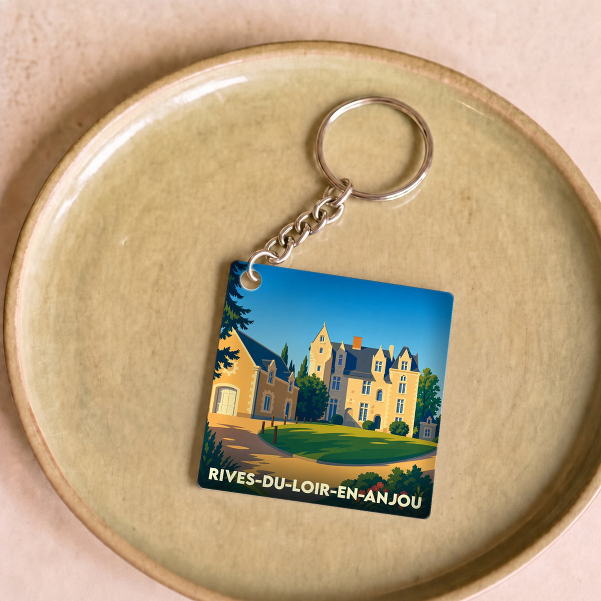 Porte-clés souvenir de la commune de Rives-du-Loir-en-Anjou avec une illustration stylisée d'un château.