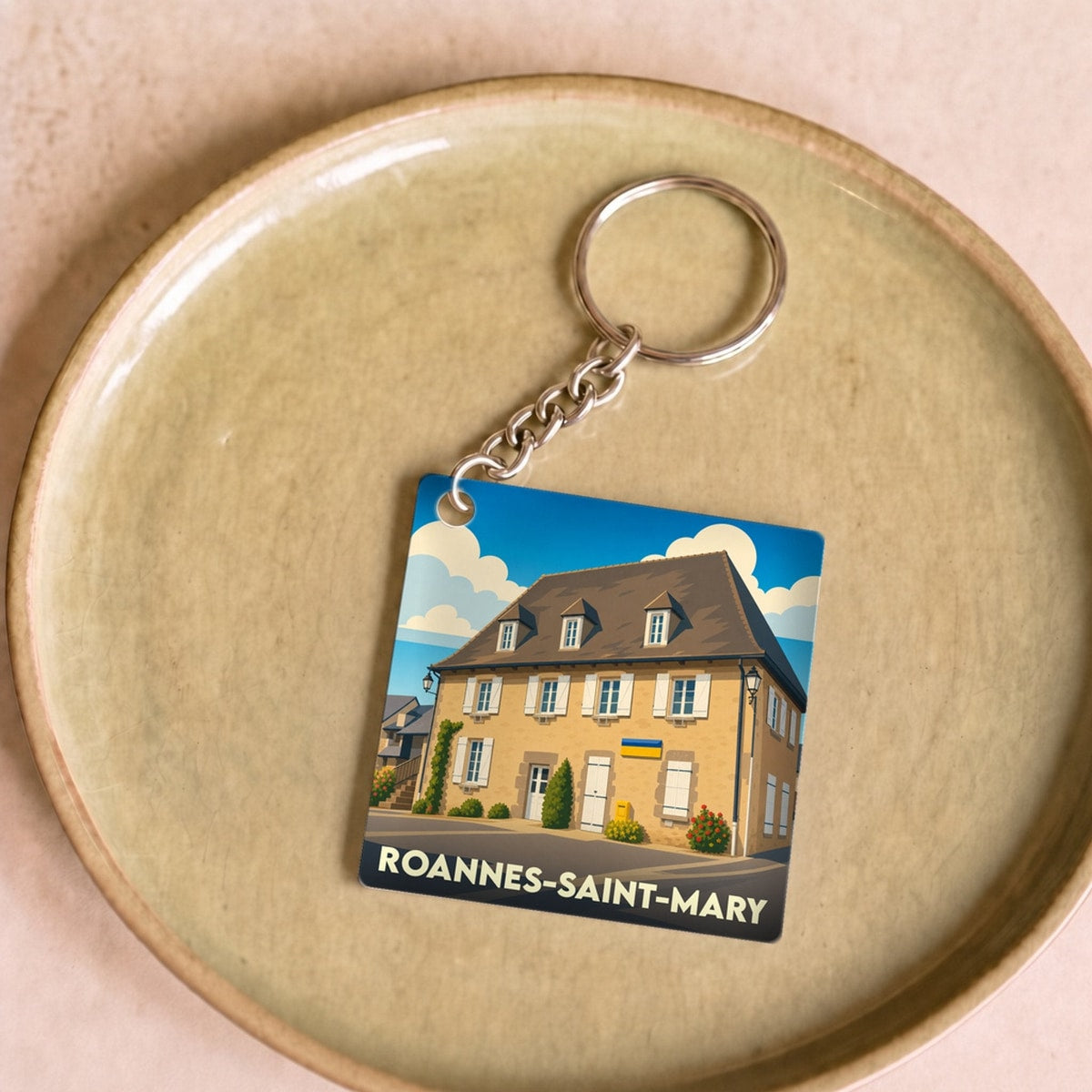 Porte-clés souvenir de la ville de Roannes-Saint-Mary avec une illustration stylisée.