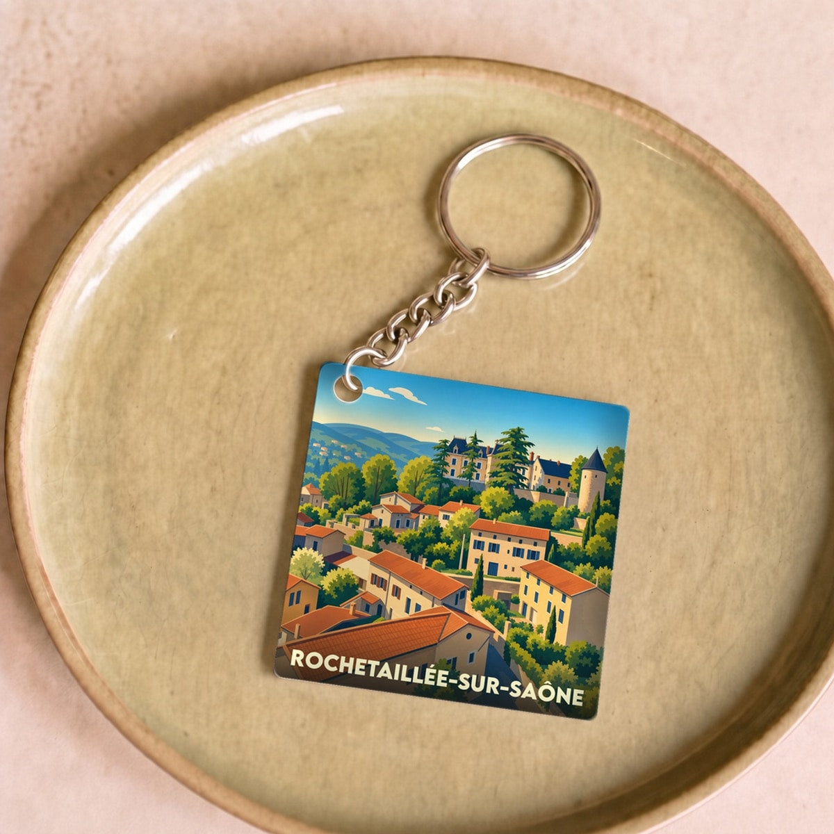 Porte-clés souvenir de Rochetaillée-sur-Saône avec une illustration stylisée du village niché dans la verdure.