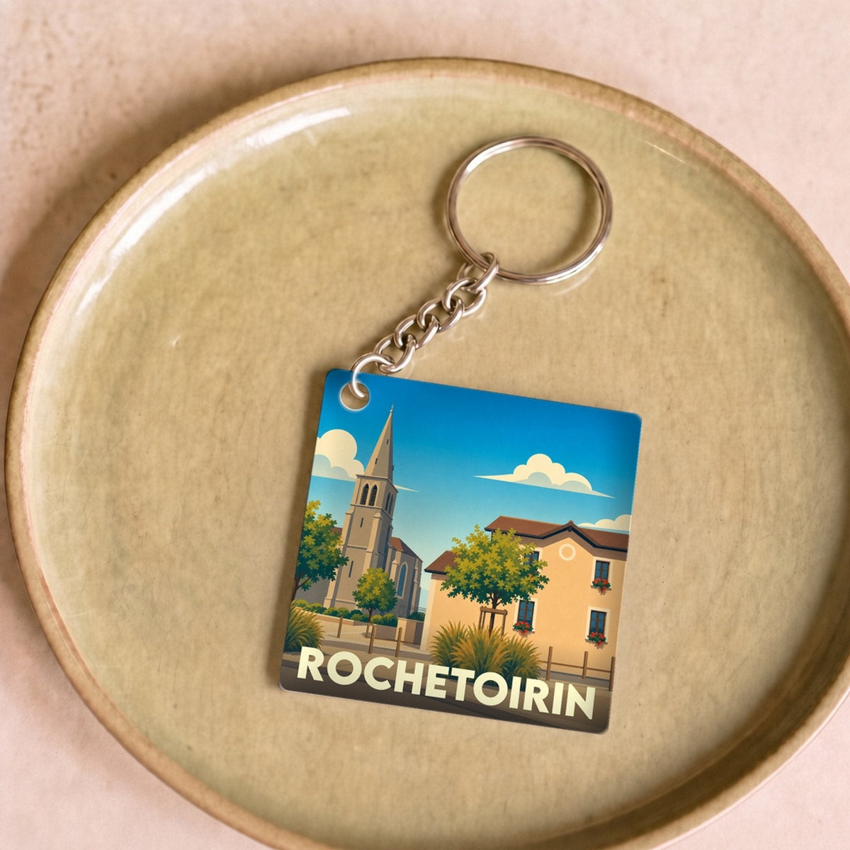 Porte-clés souvenir de la ville de Rochetoirin avec une illustration stylisée d'un paysage urbain.