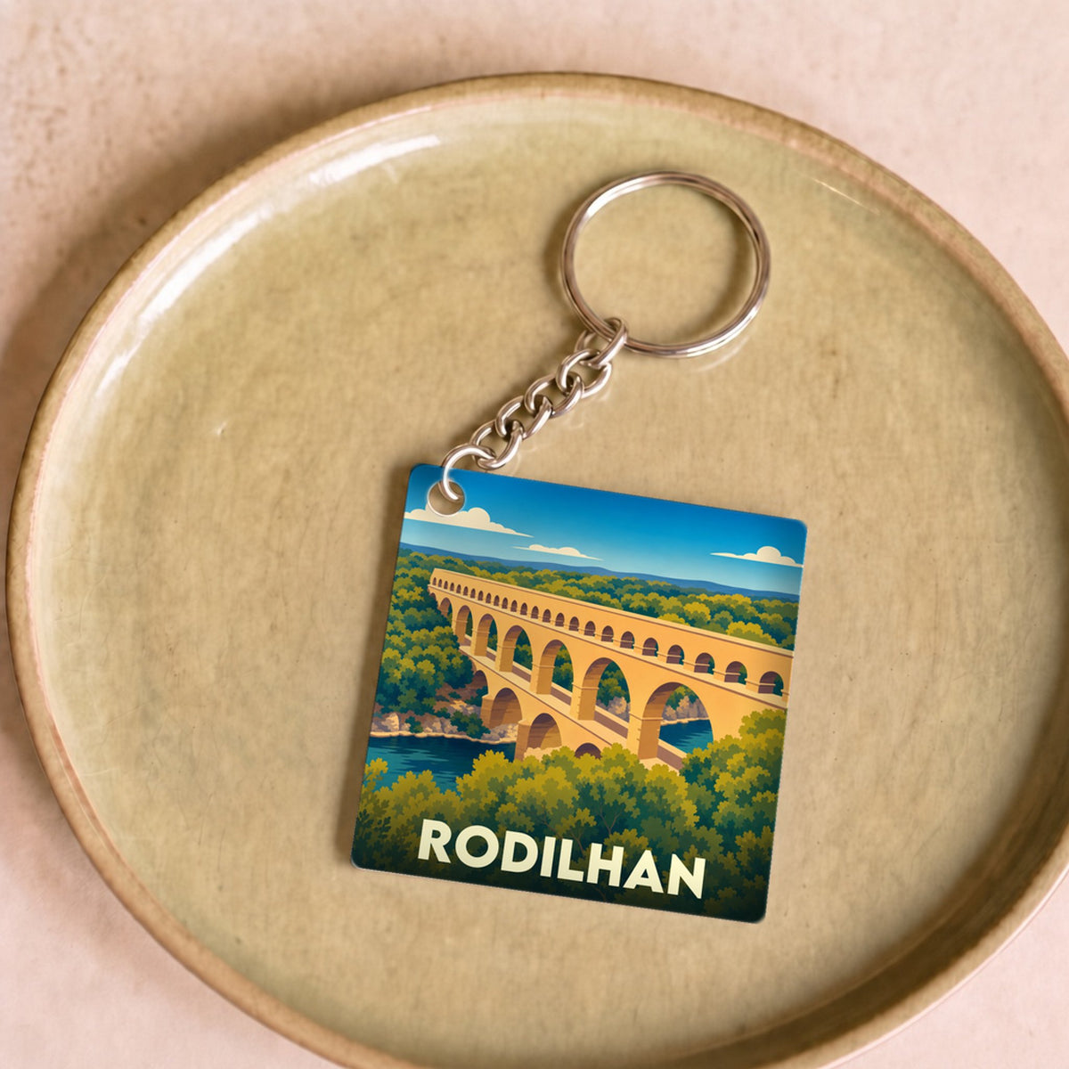 Porte-clés souvenir de la ville de Rodilhan illustré d'un aqueduc stylisé.