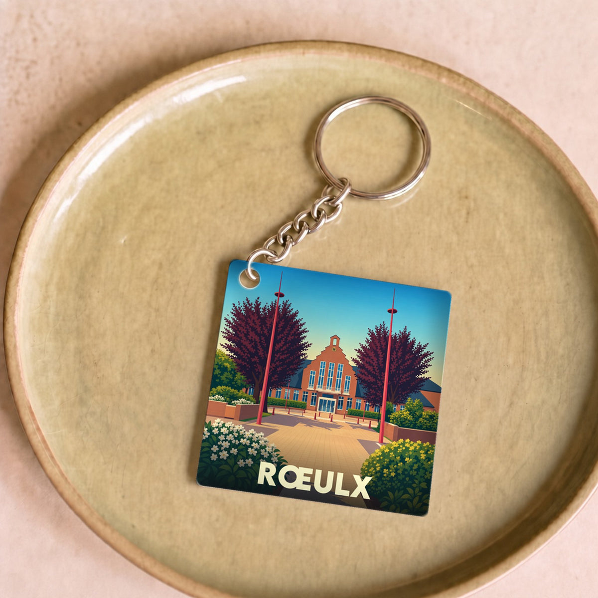 Porte-clés souvenir de la ville de Rœulx avec une illustration stylisée.