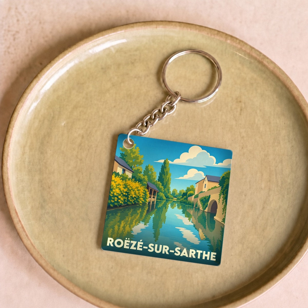 Porte-clés souvenir de la ville de Roëzé-sur-Sarthe avec une illustration stylisée des bords de la Sarthe.