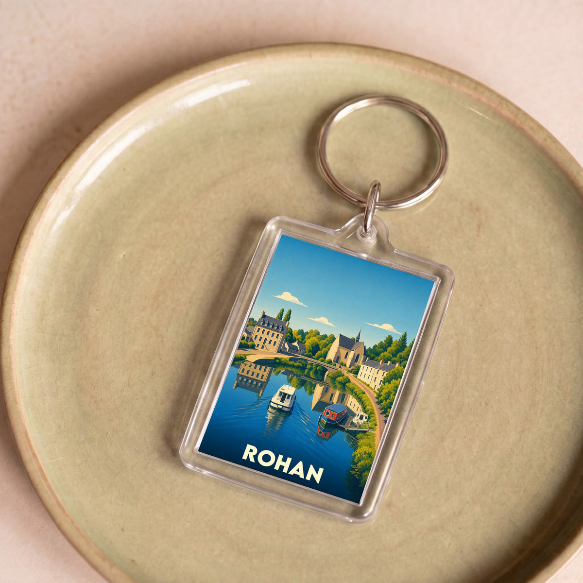 Porte-clés souvenir de la ville de Rohan avec une illustration stylisée d'un paysage fluvial.