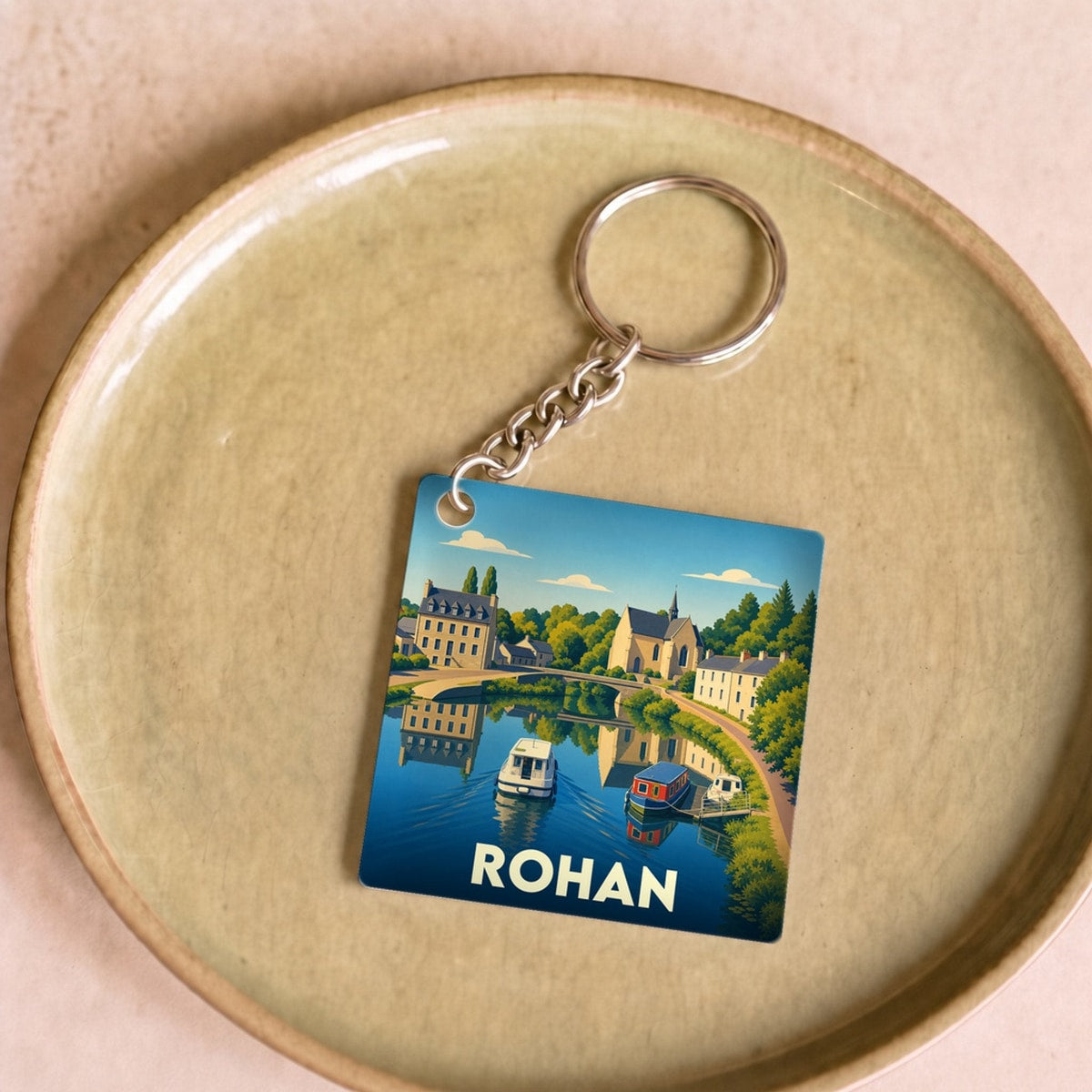 Porte-clés souvenir de la ville de Rohan avec une illustration stylisée d'un paysage fluvial.