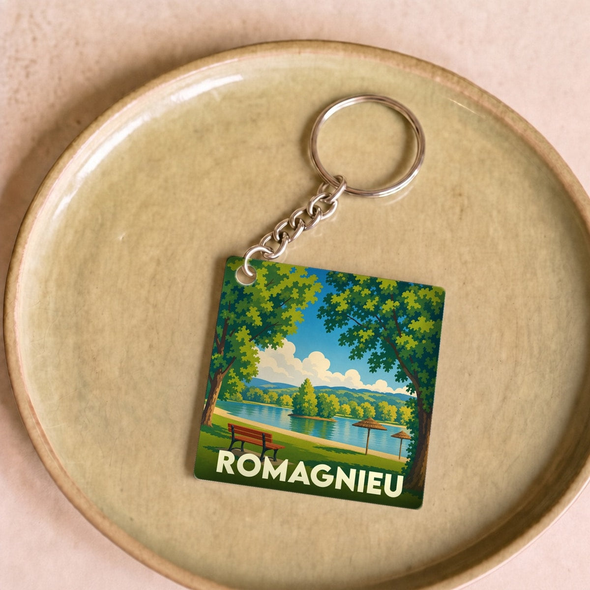 Porte-clés souvenir de la ville de Romagnieu avec une illustration stylisée d'un paysage lacustre.