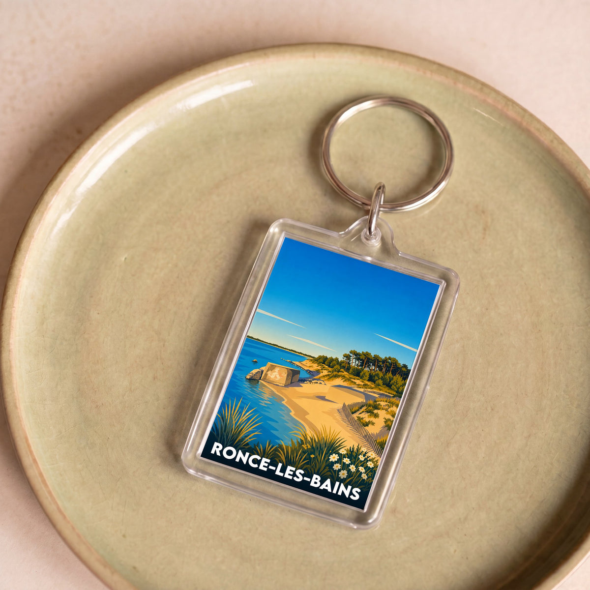 Porte-clés souvenir de la ville de Ronce-les-Bains avec une illustration stylisée d'un paysage côtier.