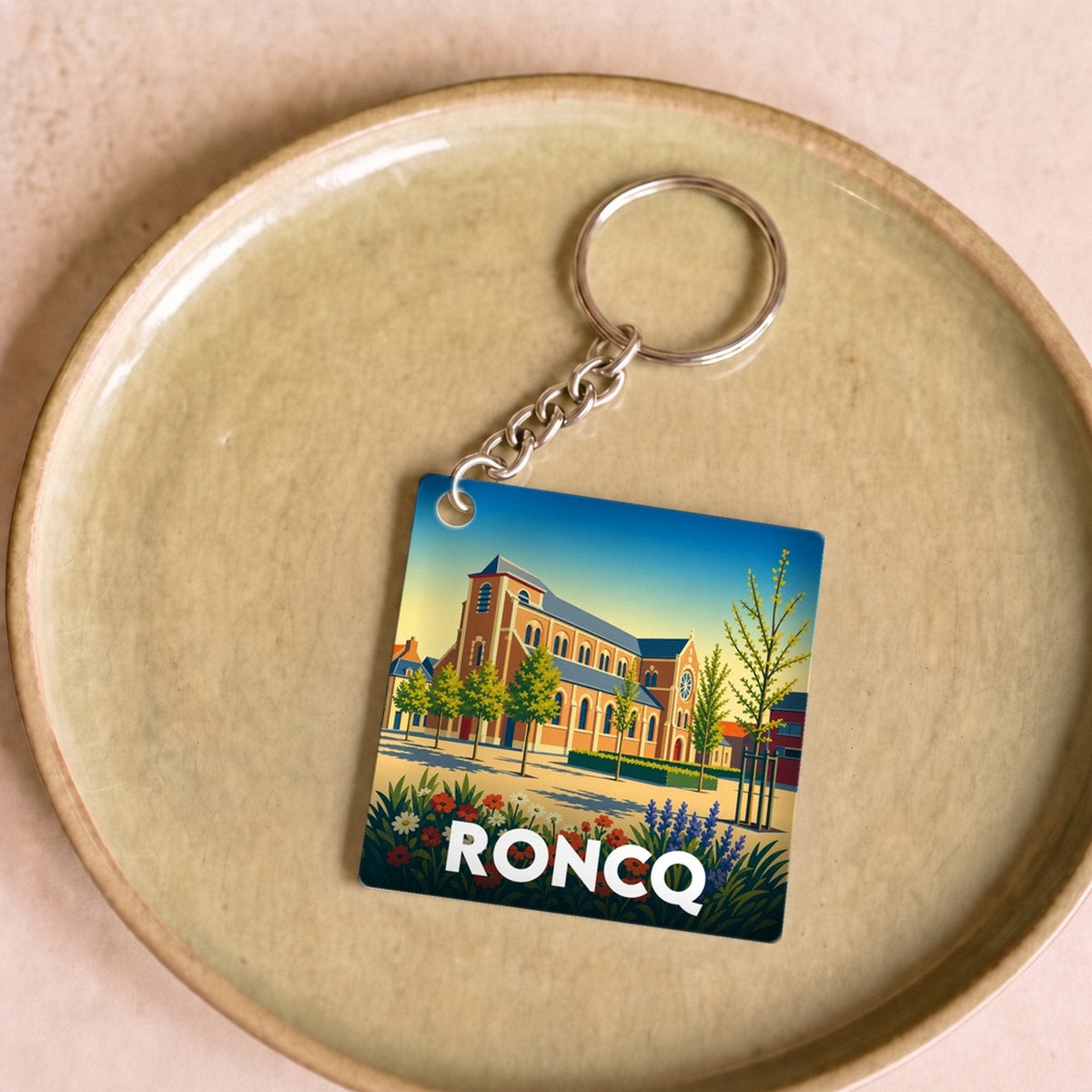 Porte-clés souvenir de la ville de Roncq avec une illustration stylisée.