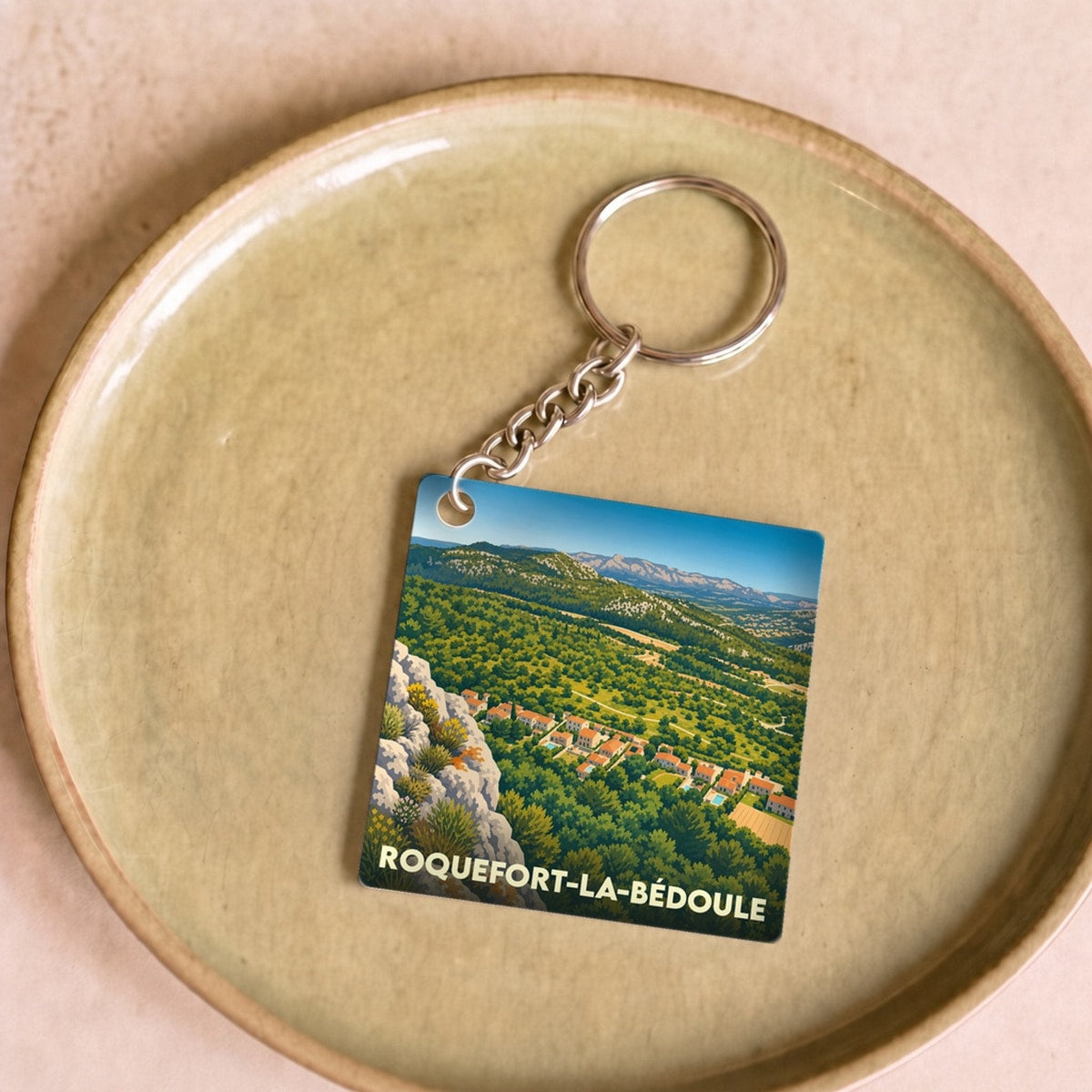 Porte-clés souvenir de la ville de Roquefort-la-Bédoule avec une illustration stylisée du paysage local.