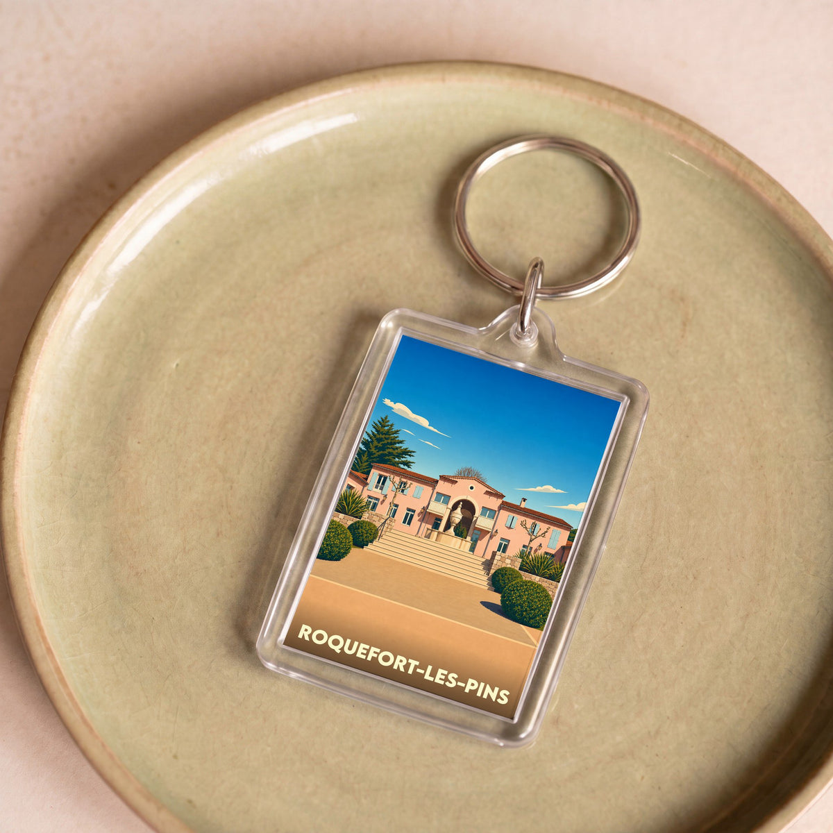 Porte-clés souvenir de la ville de Roquefort-les-Pins avec une illustration stylisée.