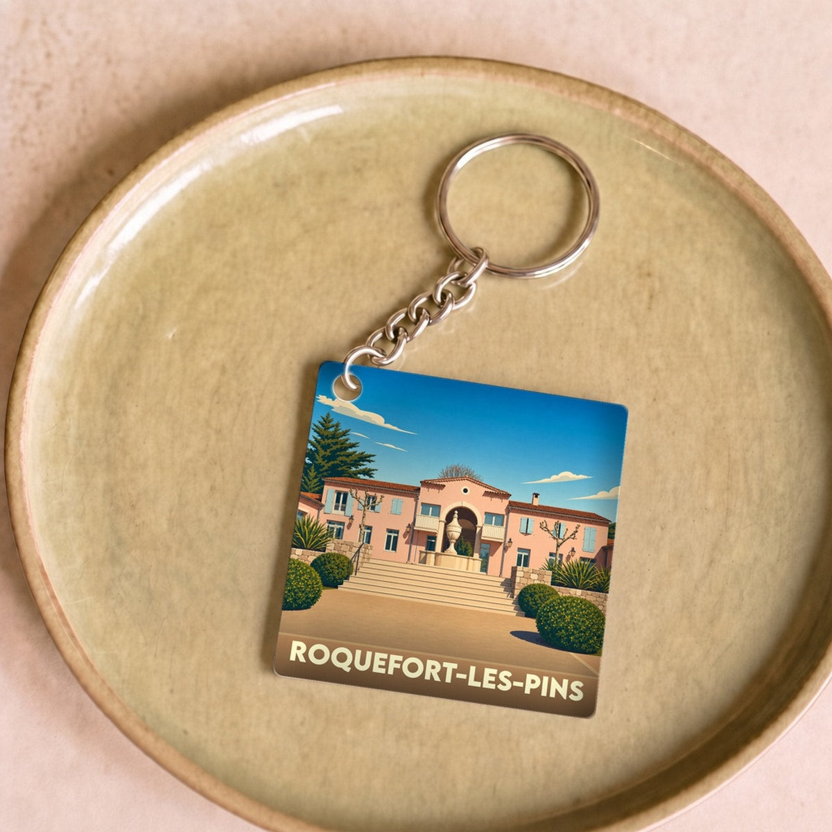 Porte-clés souvenir de la ville de Roquefort-les-Pins avec une illustration stylisée.