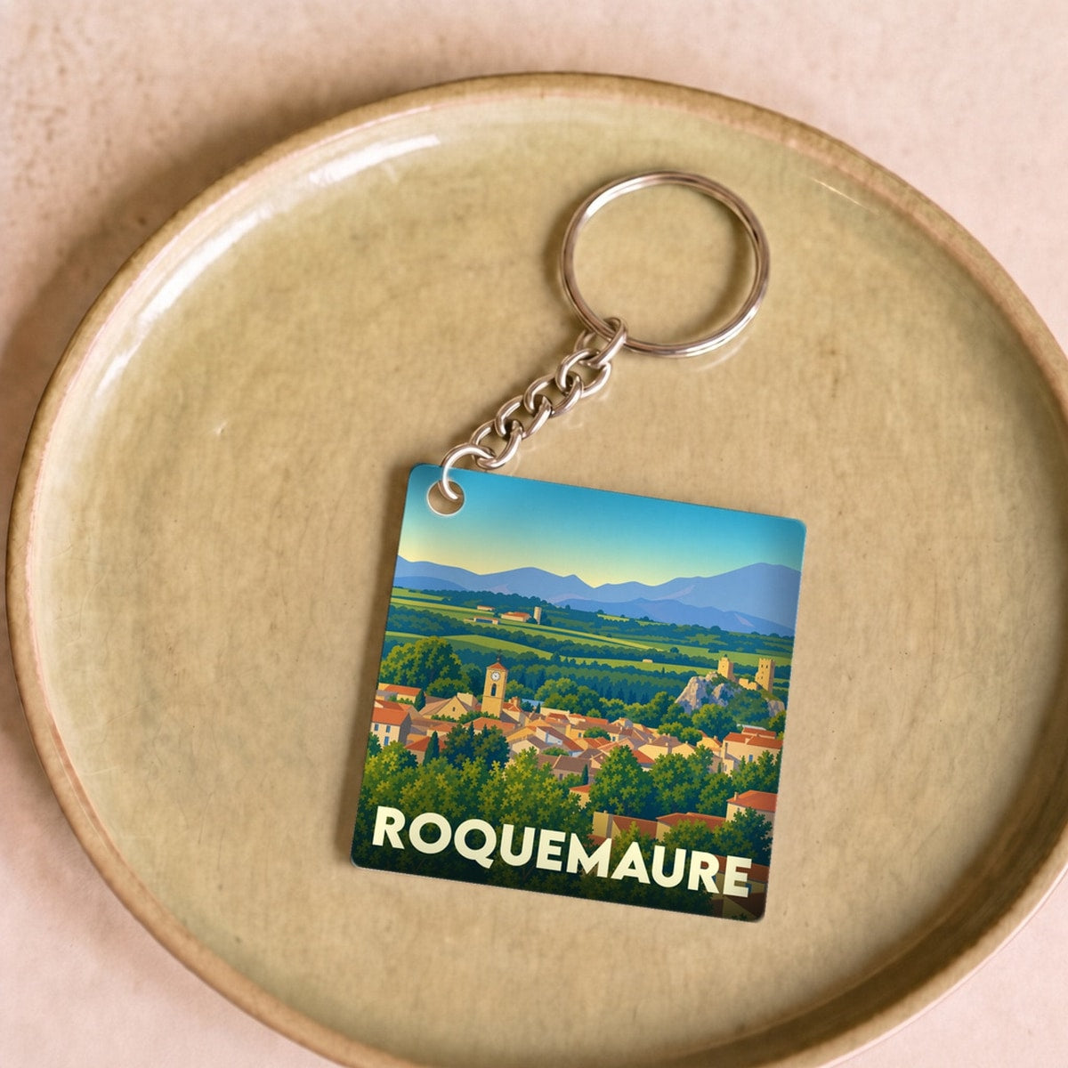 Porte-clés souvenir de la ville de Roquemaure avec une illustration stylisée du paysage urbain.