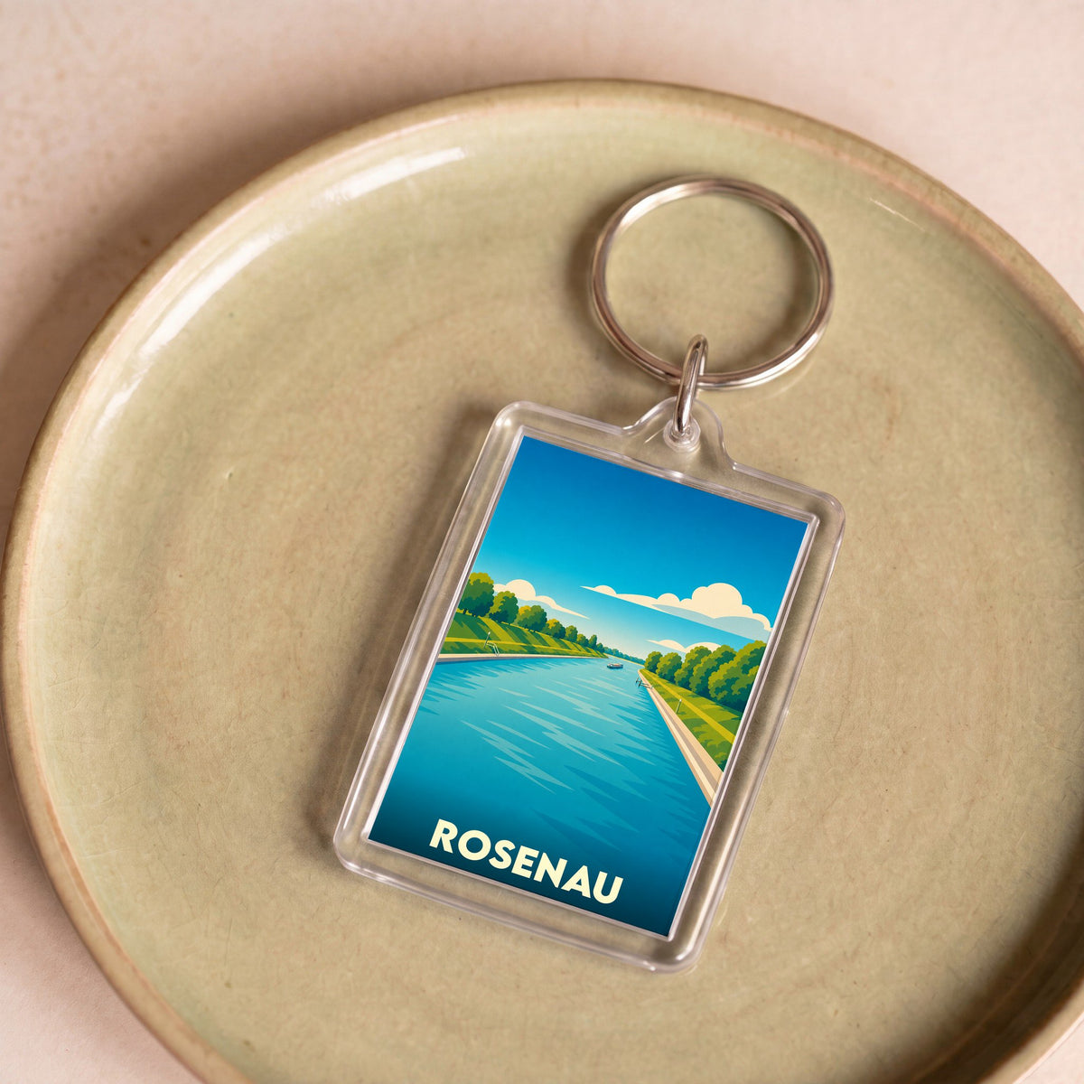 Porte-clés souvenir de la ville de Rosenau avec une illustration stylisée d'un cours d'eau bordé d'arbres.