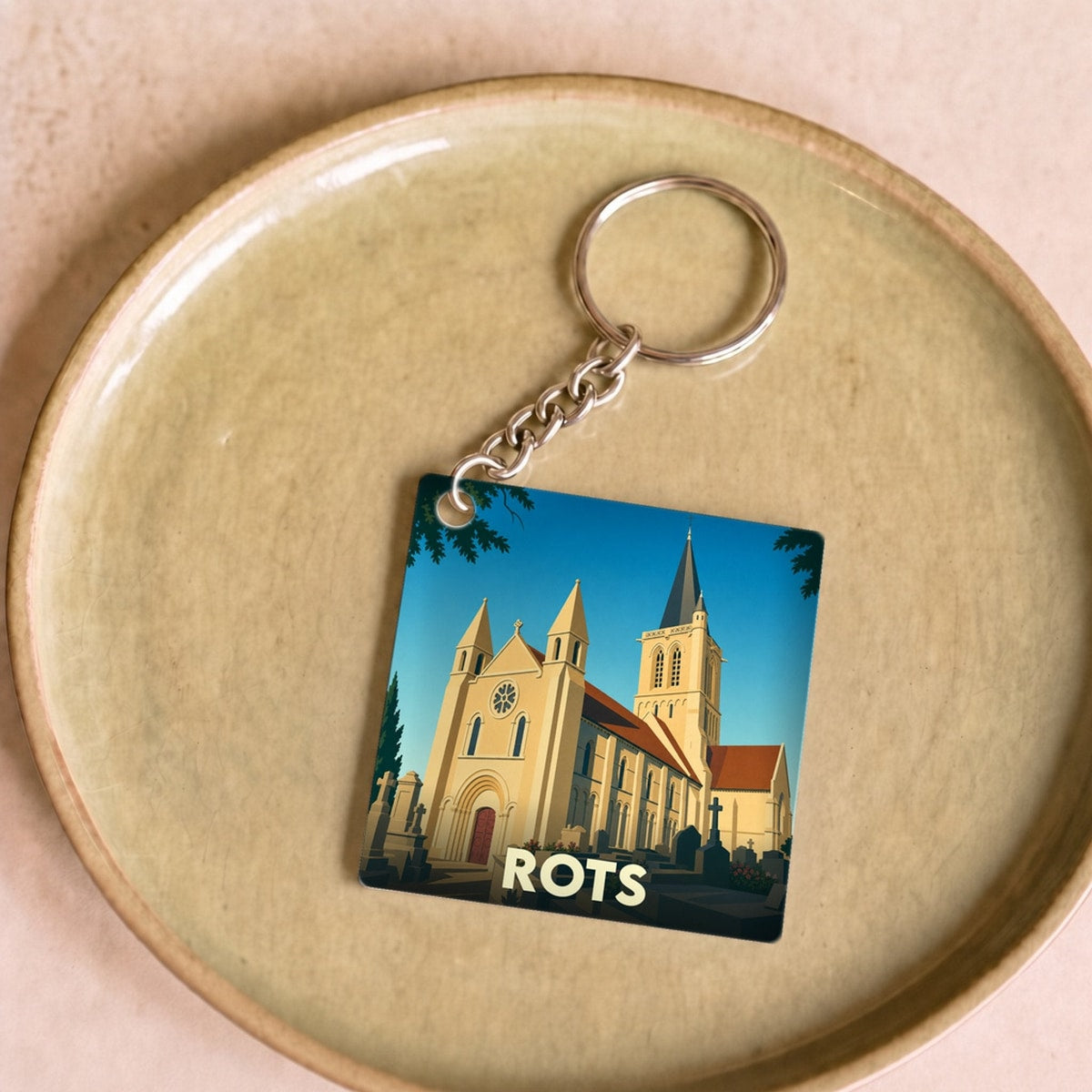 Porte-clés souvenir de la ville de Rots avec une illustration stylisée de son église.
