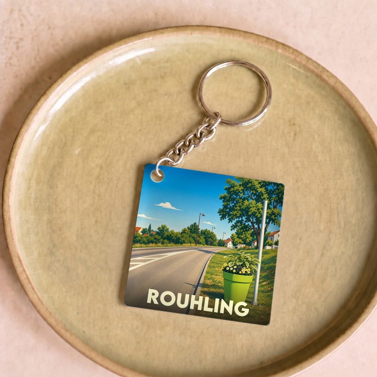 Porte-clés souvenir de la ville de Rouhling avec une illustration stylisée d'un paysage routier ensoleillé.