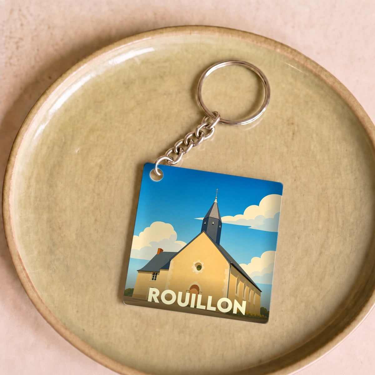 Porte-clés souvenir de la ville de Rouillon avec une illustration stylisée de son église.