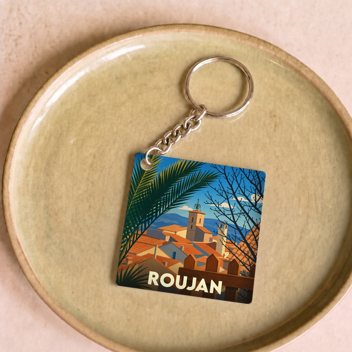 Porte-clés souvenir de la ville de Roujan avec une illustration stylisée.