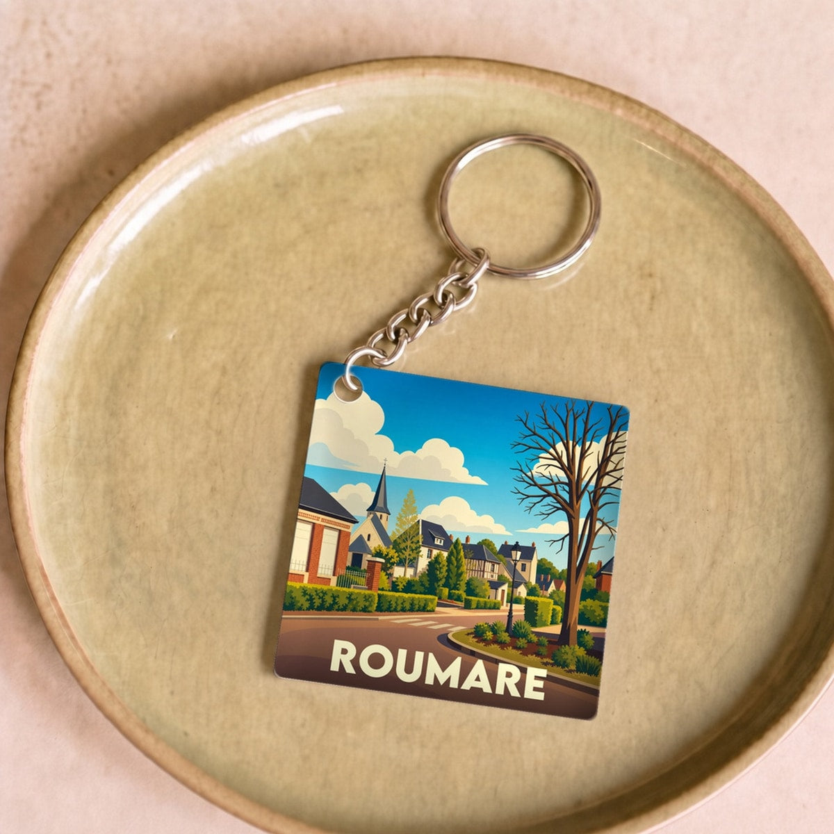 Porte-clés souvenir de la ville de Roumare avec une illustration stylisée d'un paysage urbain.