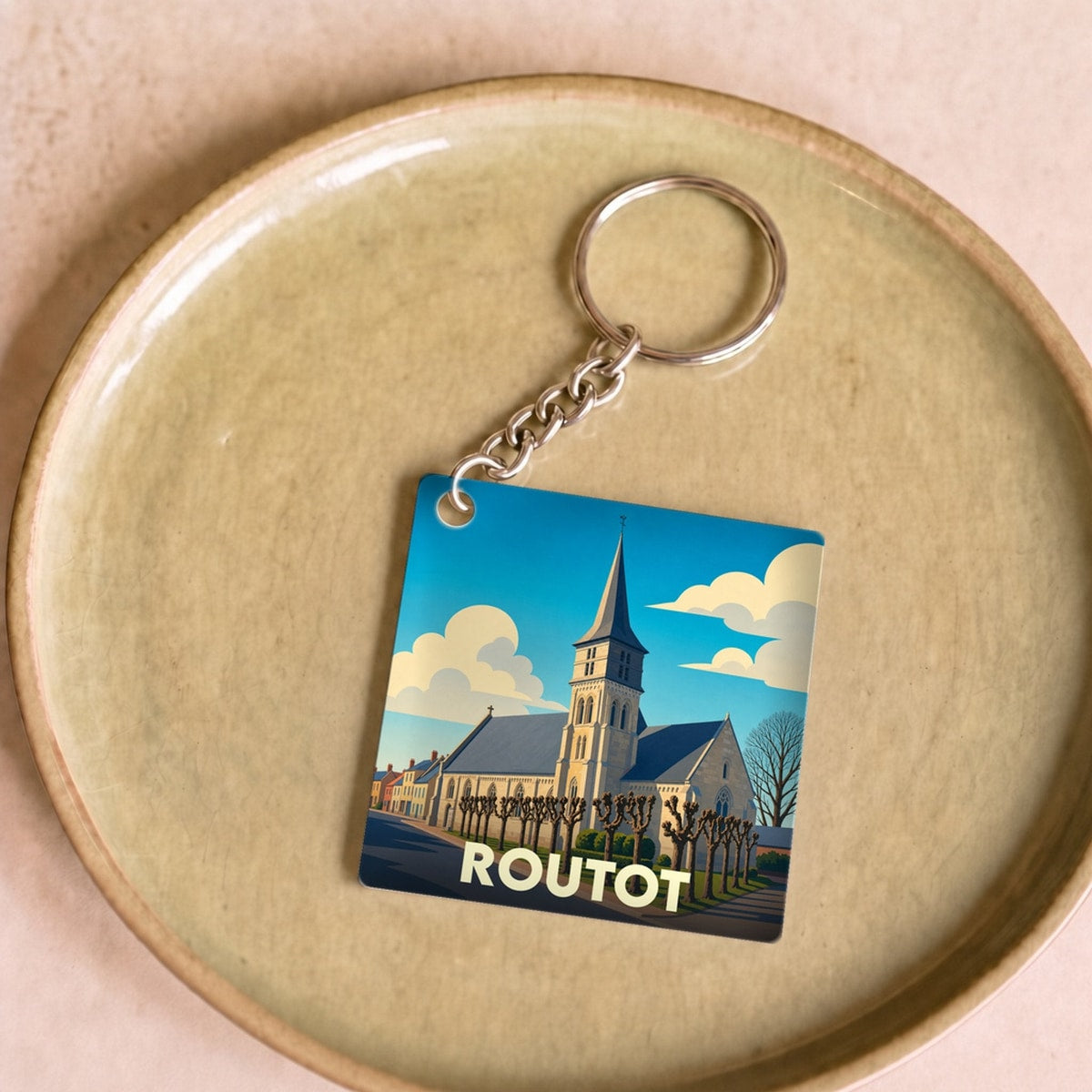 Porte-clés souvenir de la ville de Routot avec une illustration stylisée de son église.