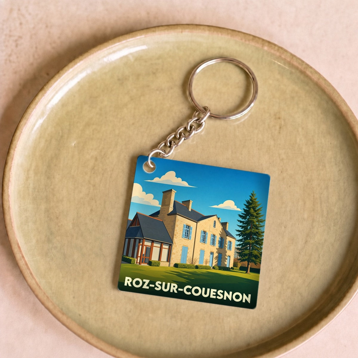 Porte-clés souvenir de la ville de Roz-sur-Couesnon avec une illustration stylisée d'une maison régionale.