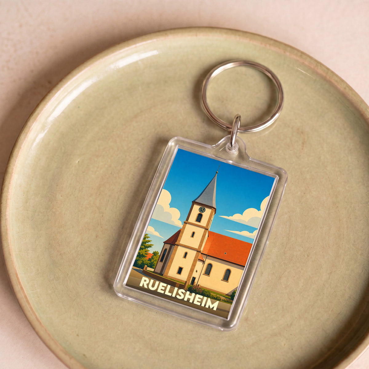 Porte-clés souvenir de la ville de Ruelisheim avec une illustration stylisée de son église.