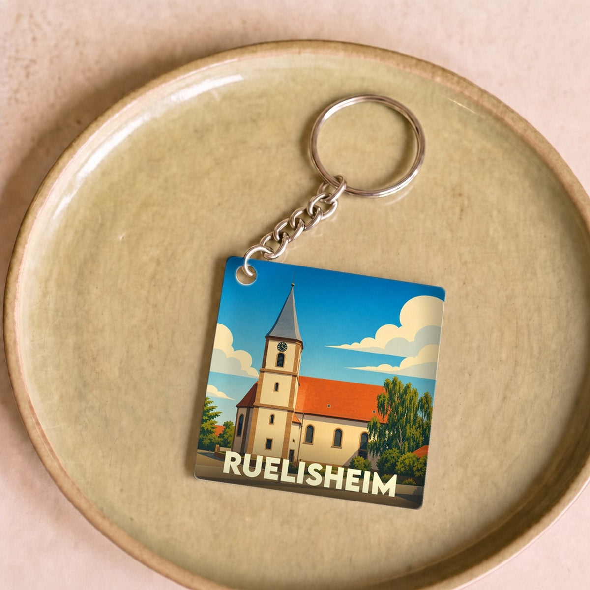 Porte-clés souvenir de la ville de Ruelisheim avec une illustration stylisée de son église.