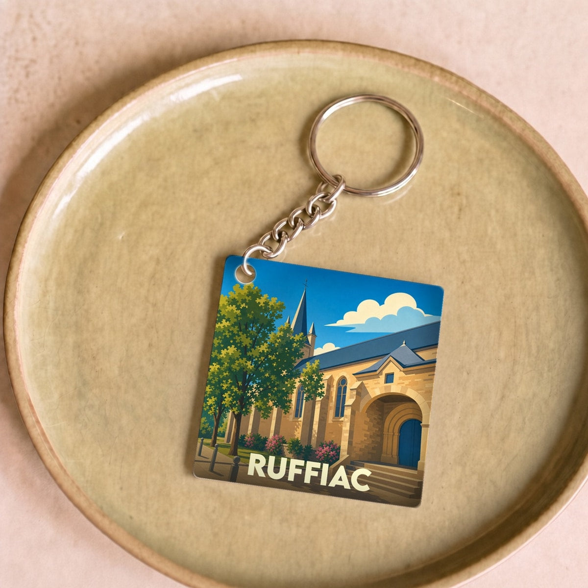 Porte-clés souvenir de la ville de Ruffiac avec une illustration stylisée d'une église sous un ciel bleu.