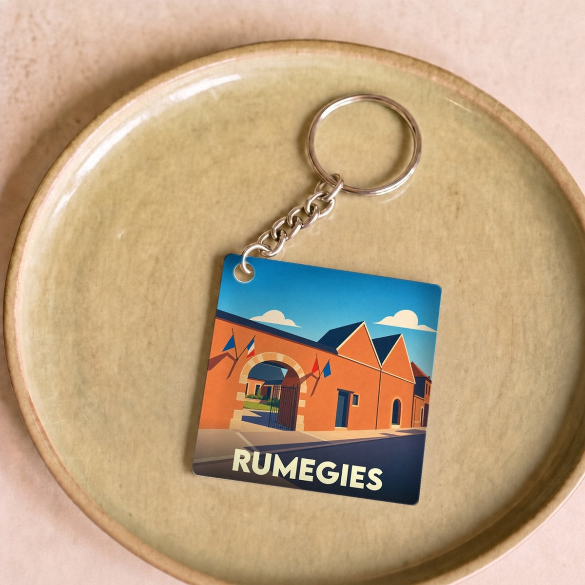 Porte-clés souvenir de la ville de Rumegies avec une illustration stylisée de ses bâtiments.