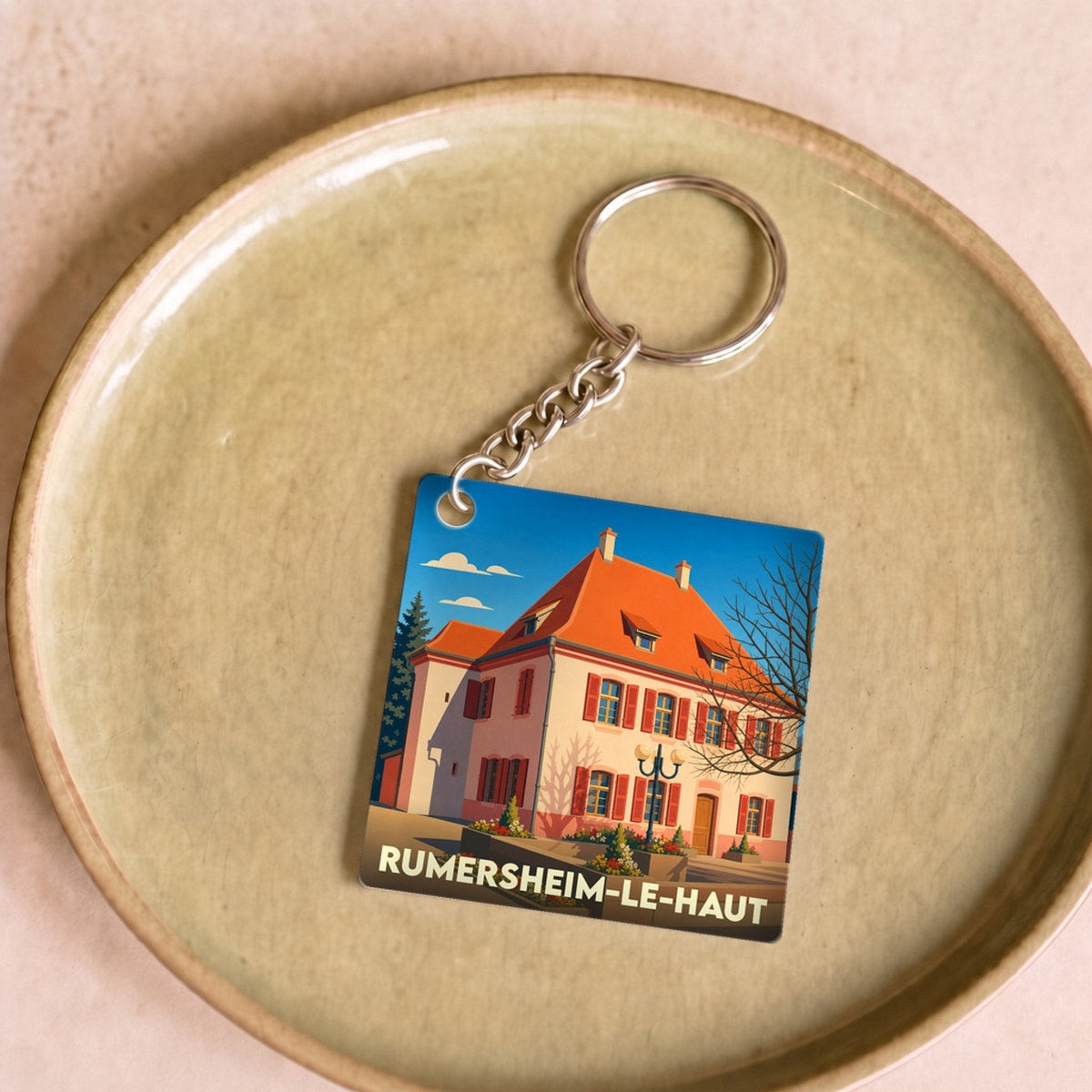 Porte-clés souvenir de la ville de Rumersheim-le-Haut avec une illustration stylisée d'un bâtiment traditionnel.
