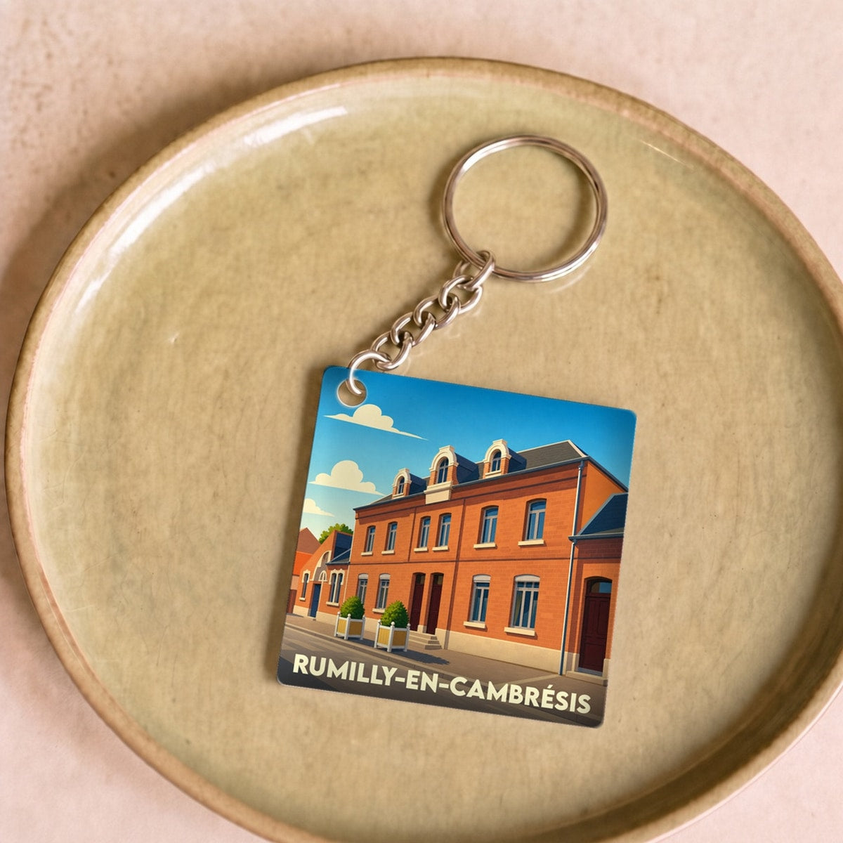 Porte-clés souvenir de la ville de Rumilly-en-Cambrésis avec une illustration stylisée.
