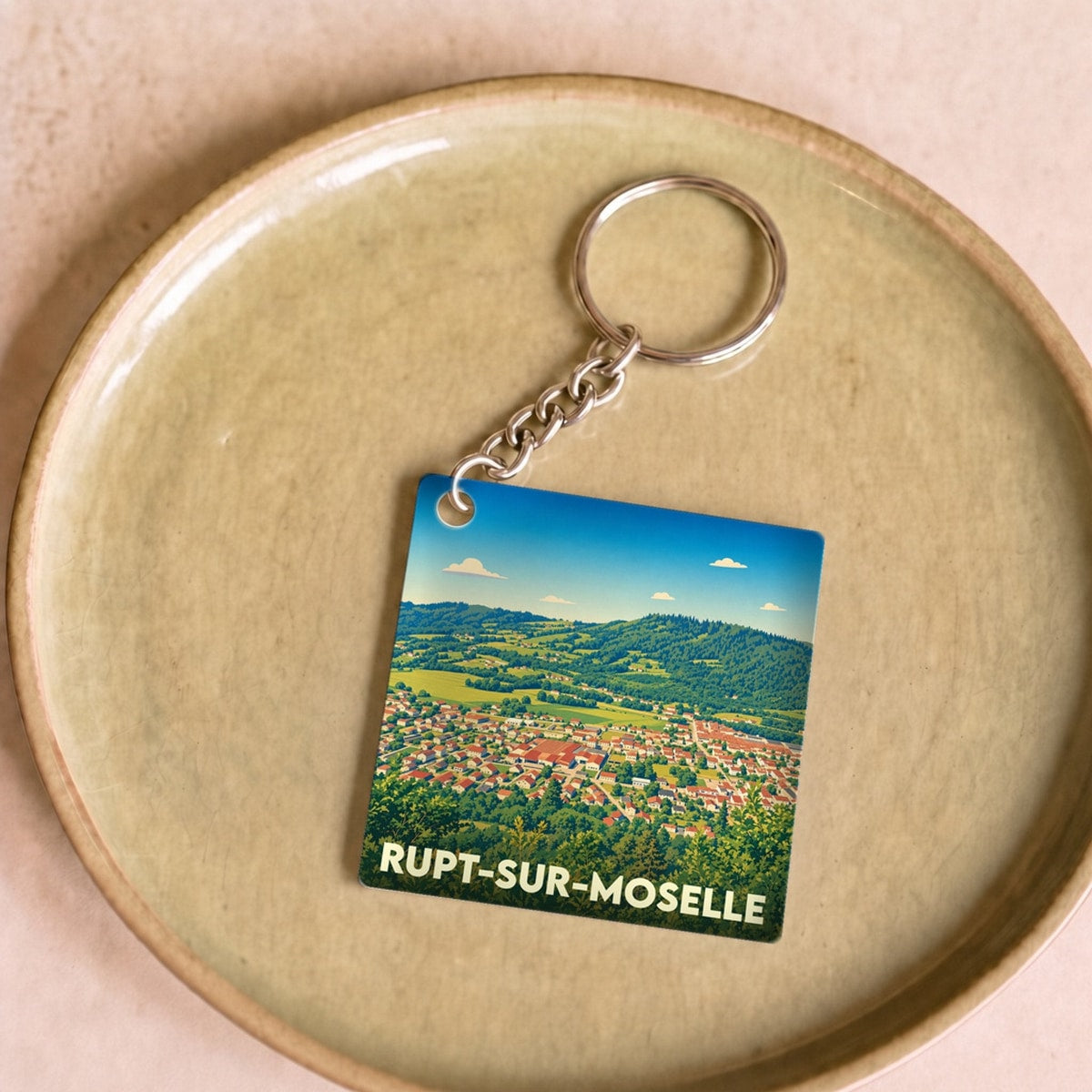 Porte-clés souvenir de la ville de Rupt-sur-Moselle avec une illustration paysagère stylisée.