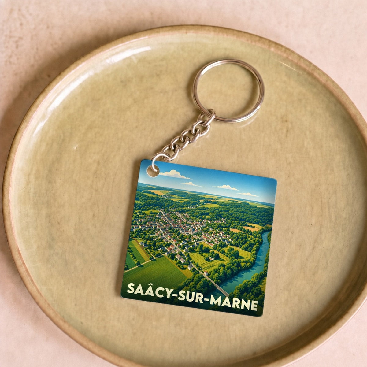 Porte-clés souvenir de la ville de Saâcy-sur-Marne avec une illustration paysagère stylisée.