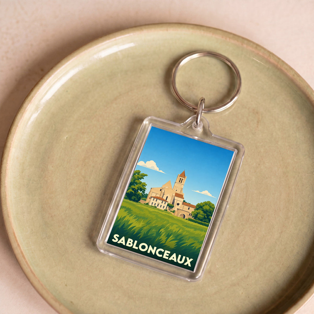 Porte-clés souvenir de la ville de Sablonceaux avec une illustration stylisée de son abbaye.