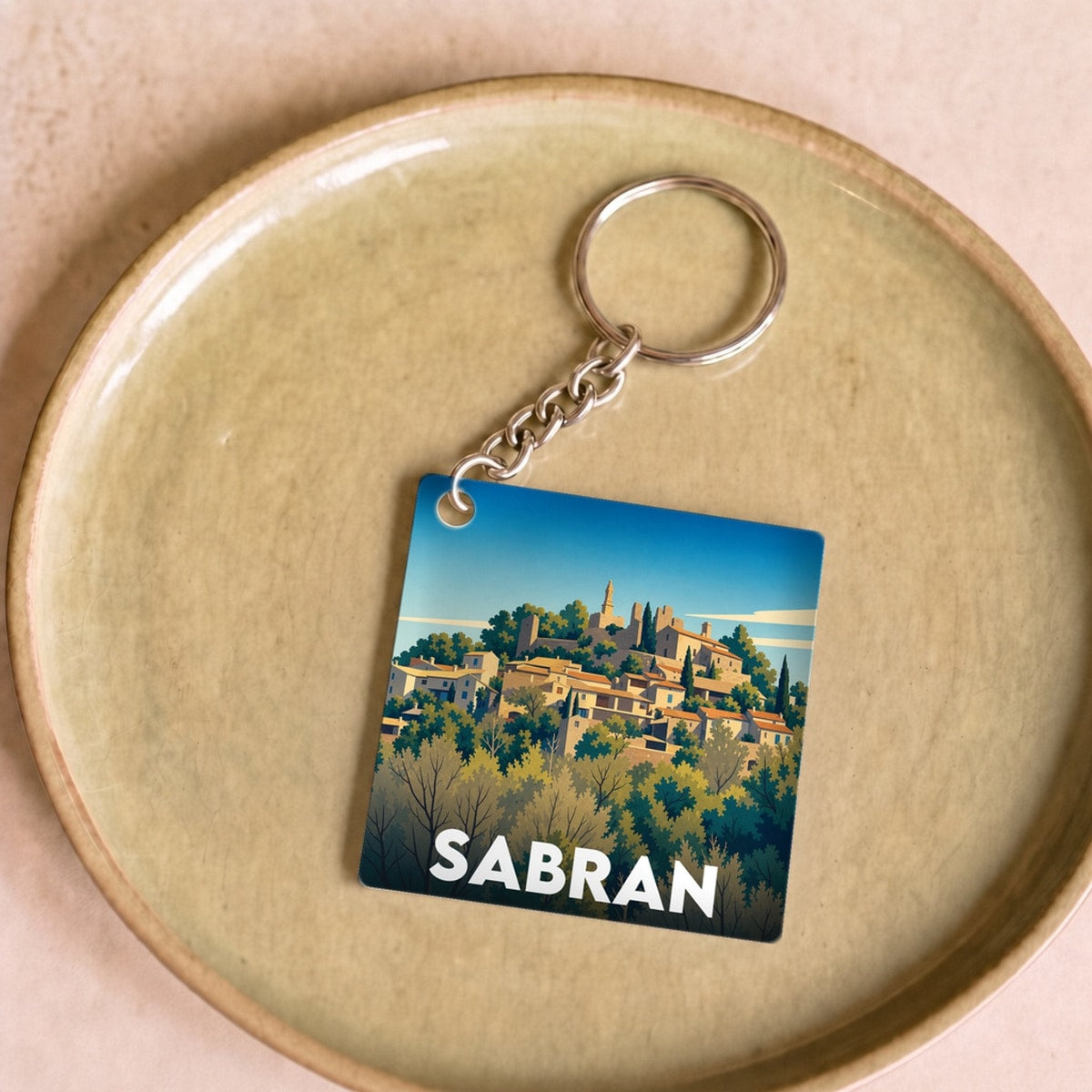 Porte-clés souvenir de la ville de Sabran avec une illustration stylisée.