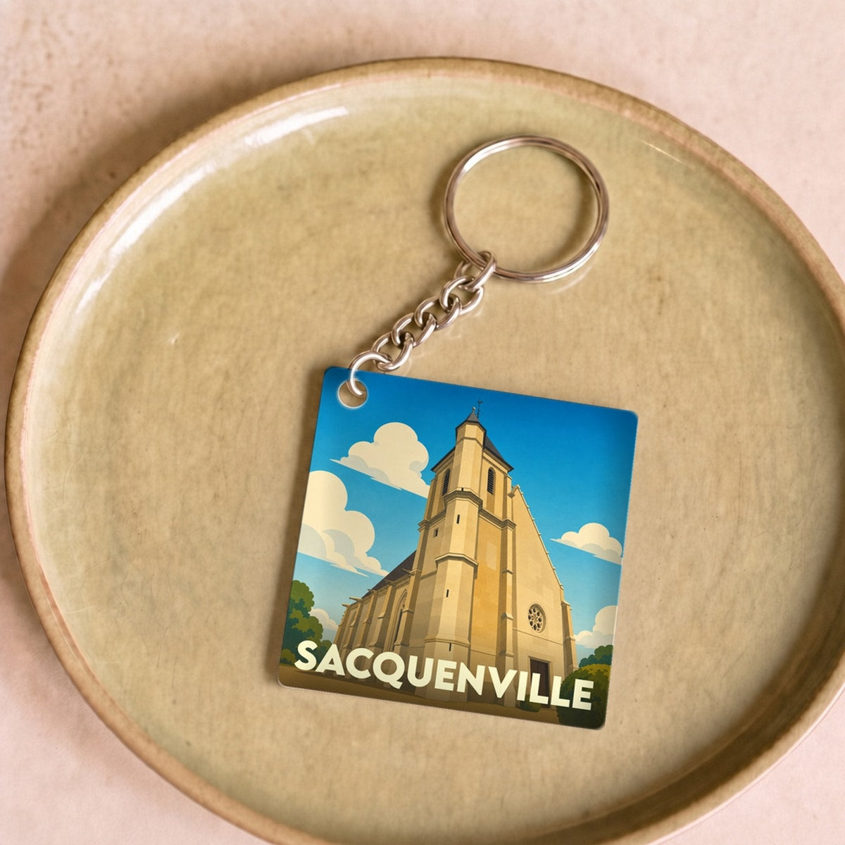 Porte-clés souvenir de la ville de Sacquenville avec une illustration stylisée de son église.