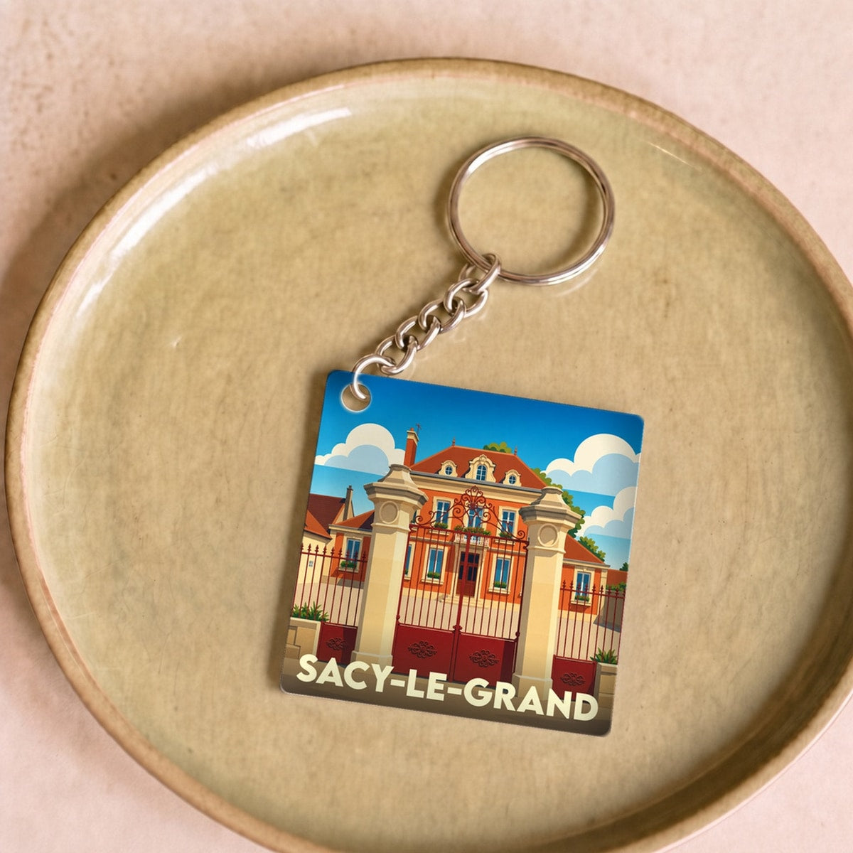 Porte-clés souvenir de la ville de Sacy-le-Grand avec une illustration stylisée d'un domaine historique.