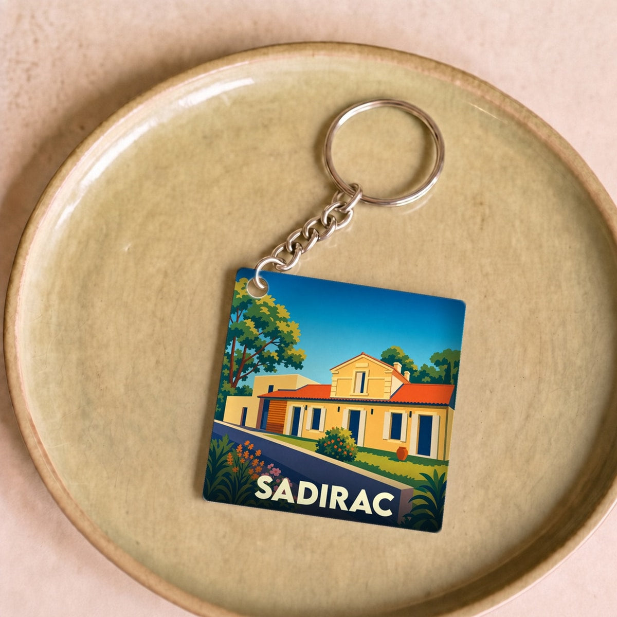 Porte-clés souvenir de la ville de Sadirac avec une illustration stylisée.