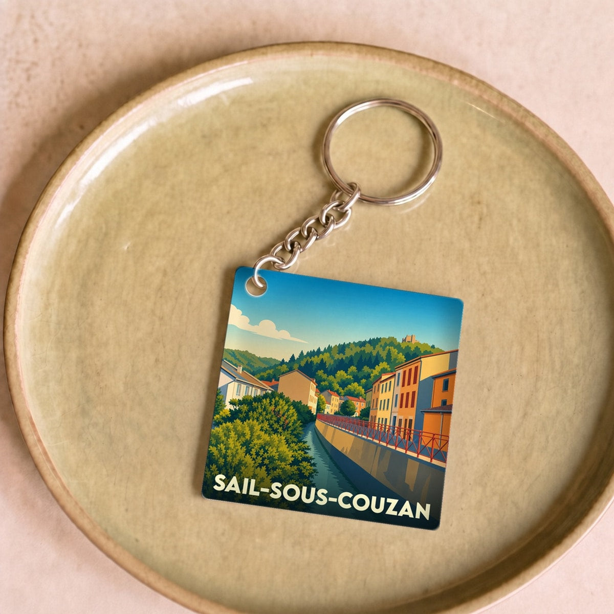 Porte-clés souvenir de Sail-sous-Couzan avec une illustration stylisée du village et de sa rivière.
