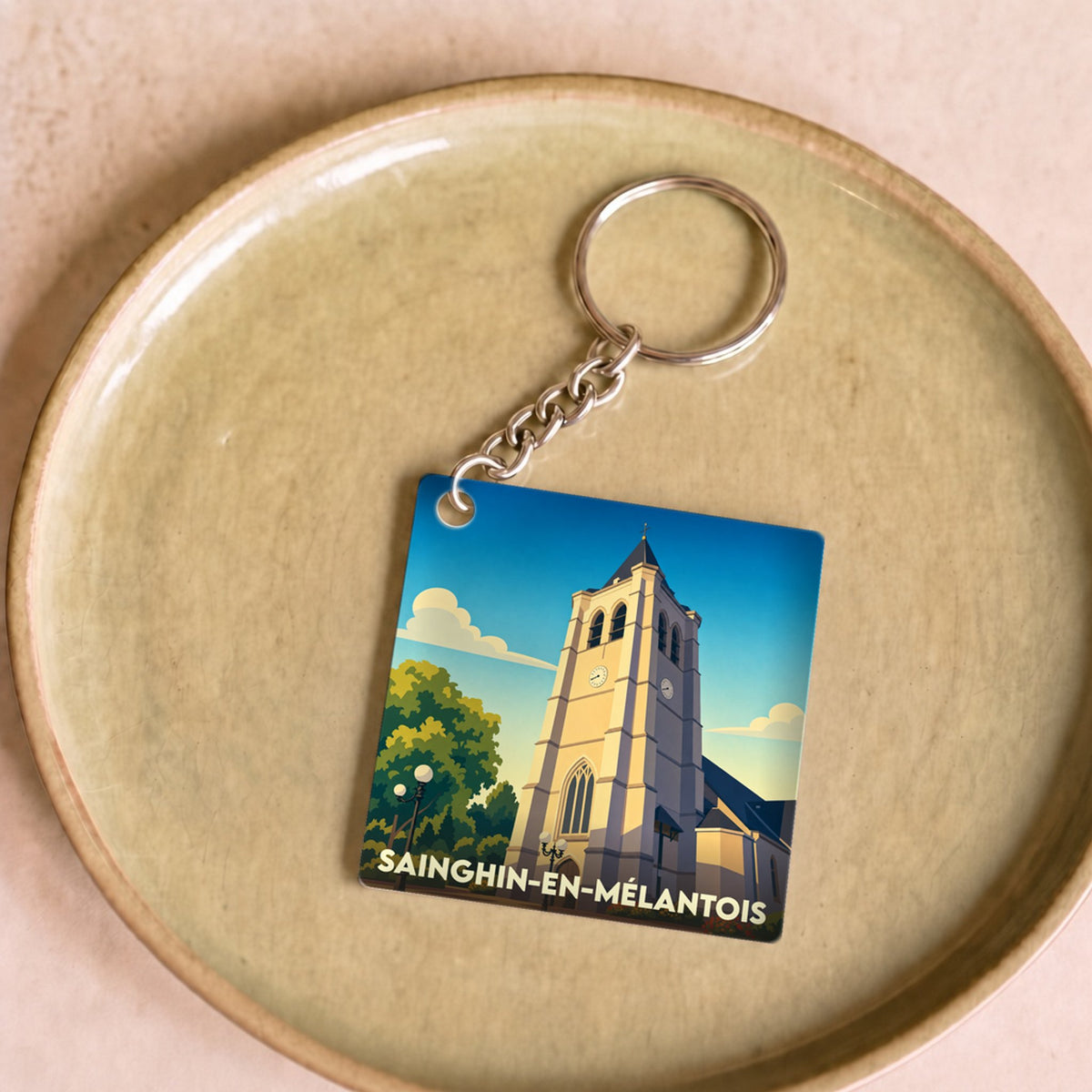 Porte-clés souvenir de la ville de Sainghin-en-Mélantois avec une illustration stylisée de son église.