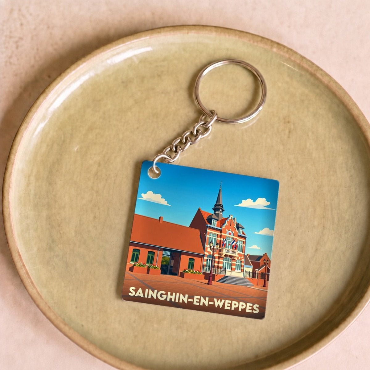 Porte-clés souvenir de la ville de Sainghin-en-Weppes avec une illustration stylisée de son hôtel de ville.