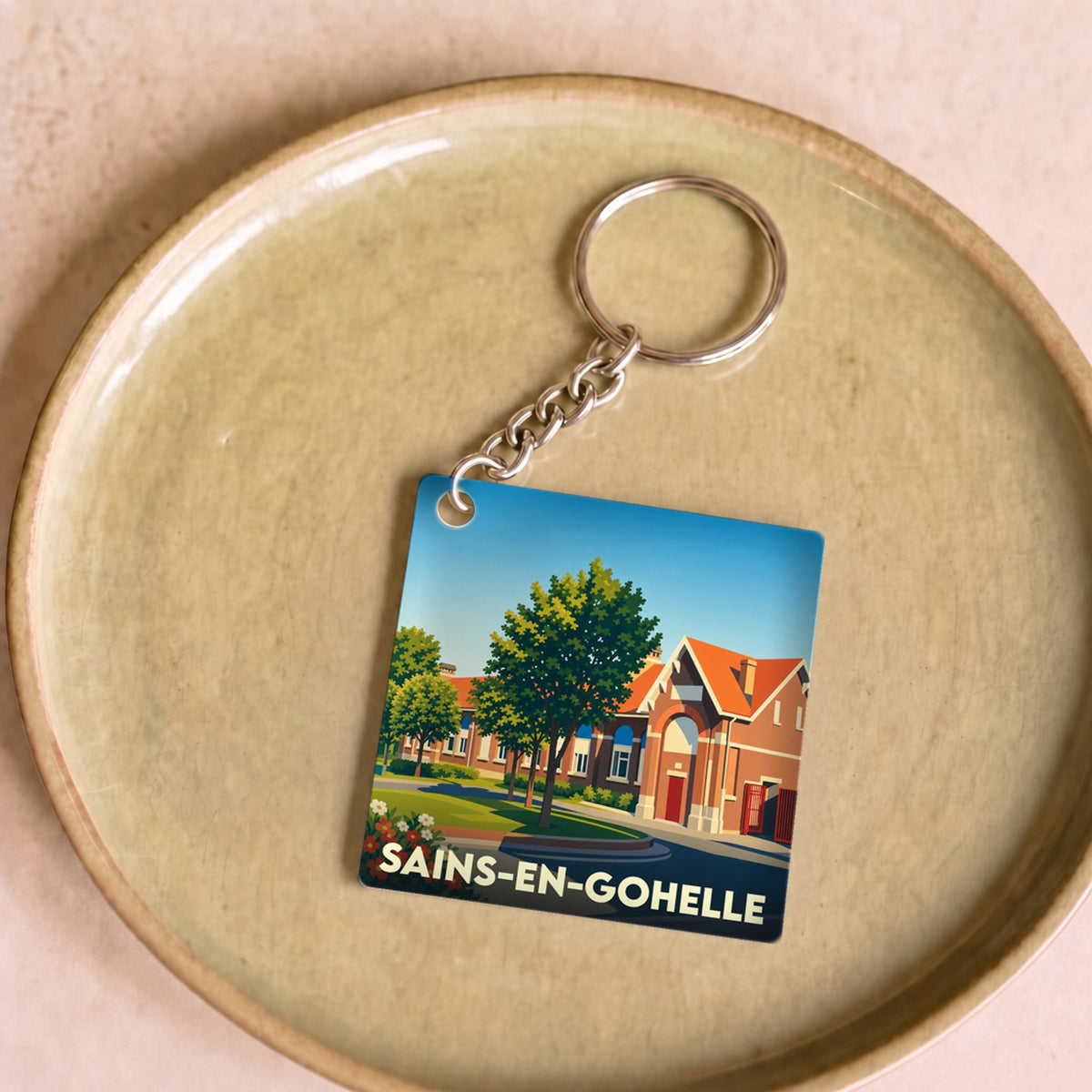 Porte-clés souvenir de la ville de Sains-en-Gohelle avec une illustration stylisée.