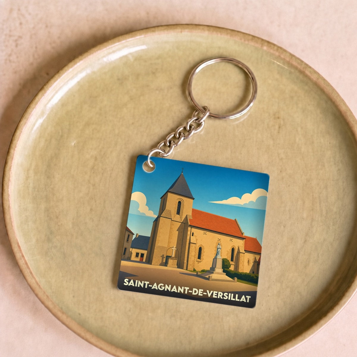 Porte-clés souvenir de la ville de Saint-Agnant-de-Versillat avec une illustration stylisée de son église.