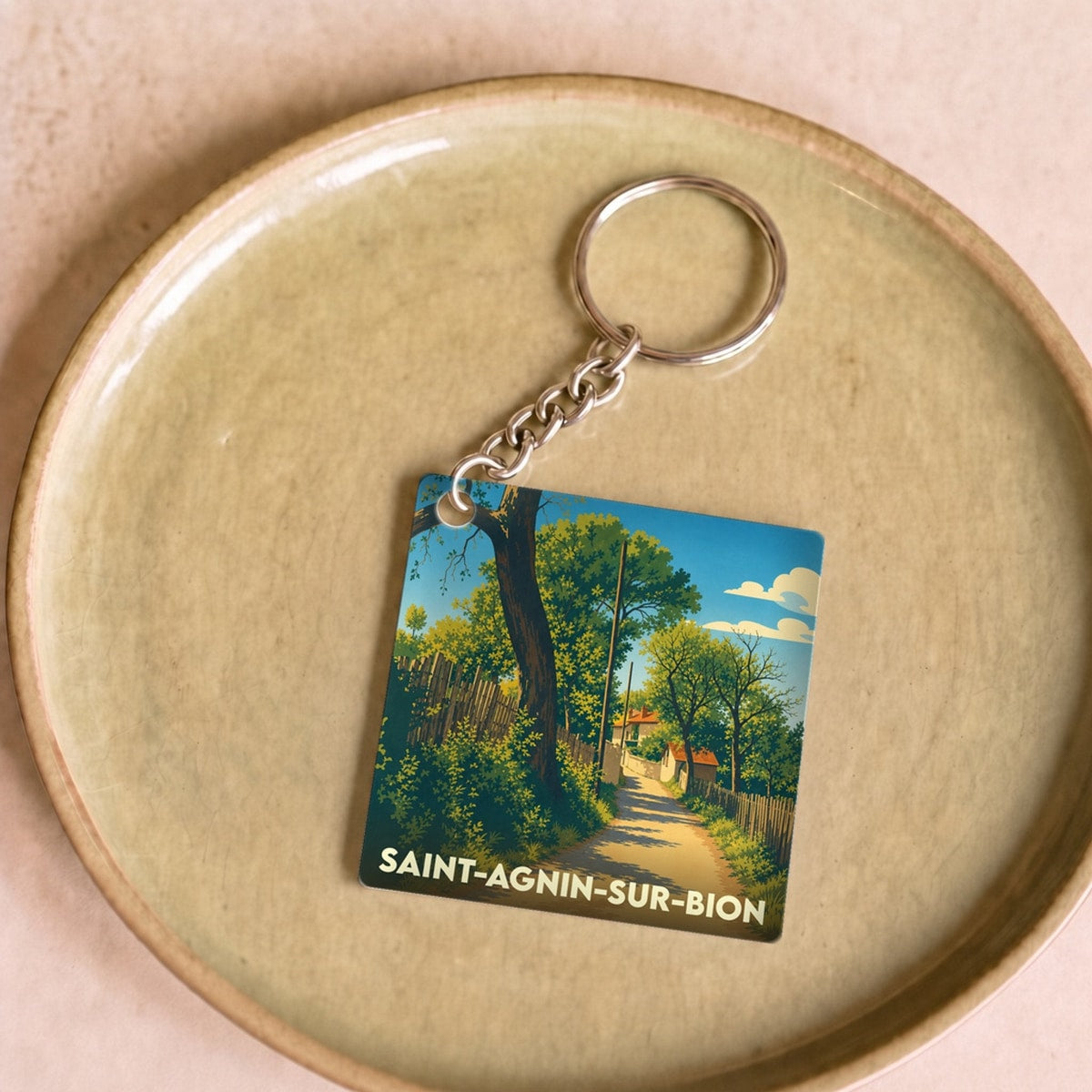 Porte-clés souvenir de la ville de Saint-Agnin-sur-Bion avec une illustration de chemin arboré.