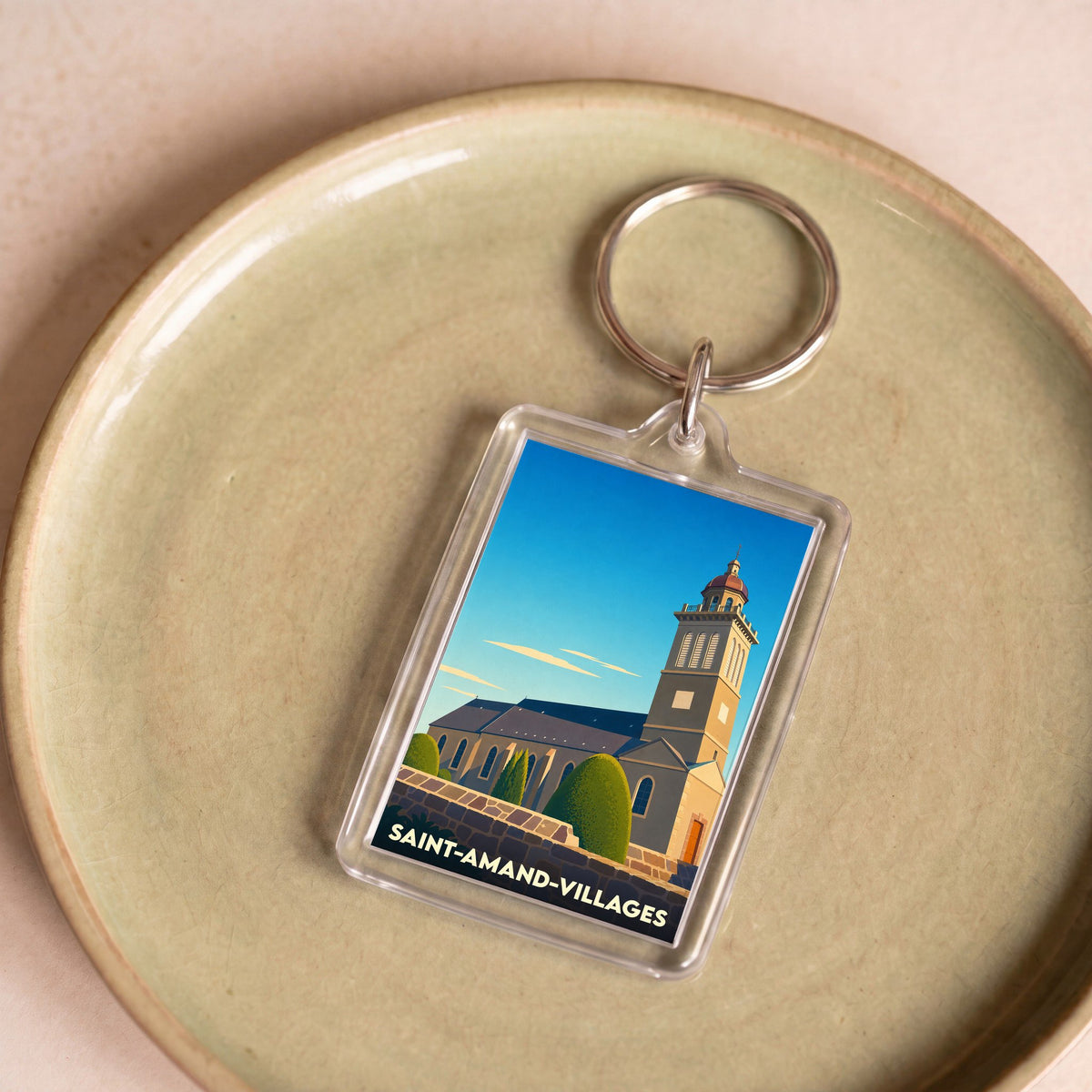 Porte-clés souvenir de la commune de Saint-Amand-Villages avec une illustration stylisée de son église.
